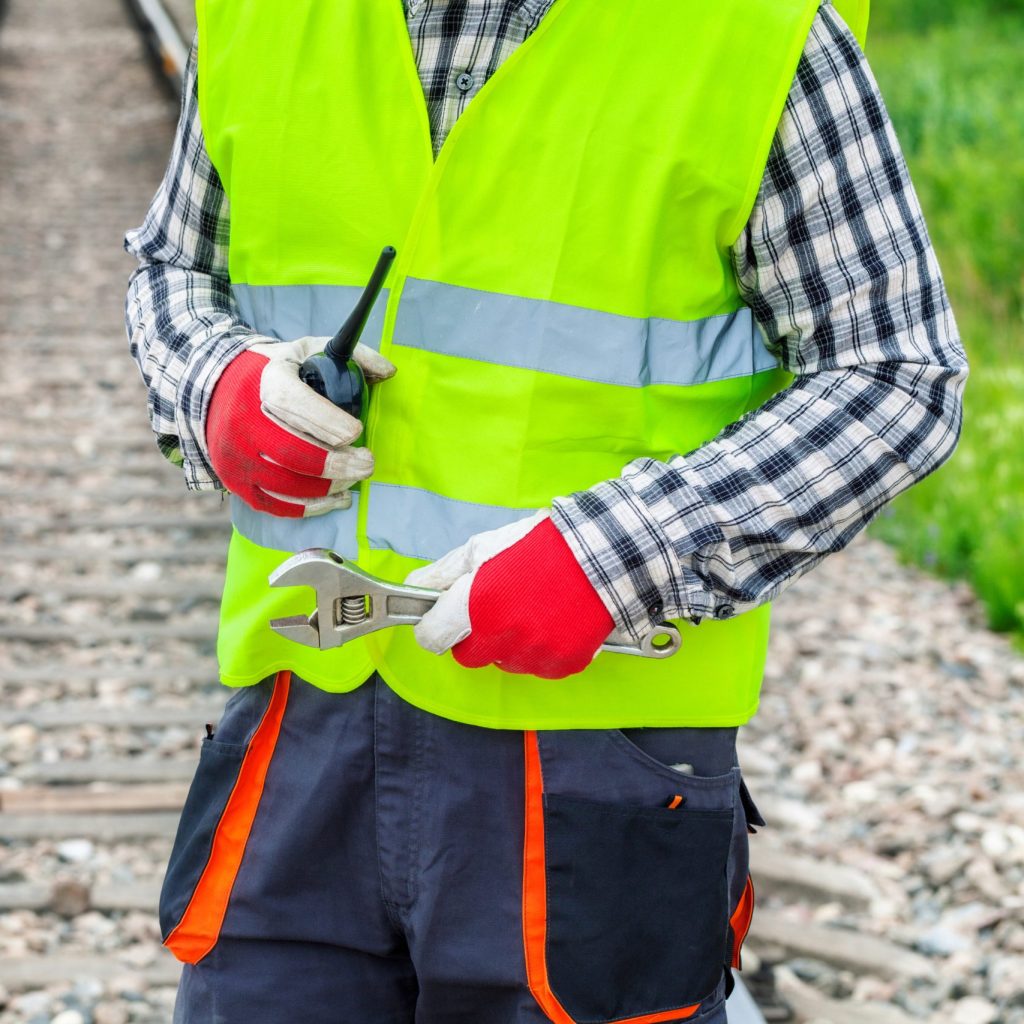 Worker with walkie talkie and wrench on railway